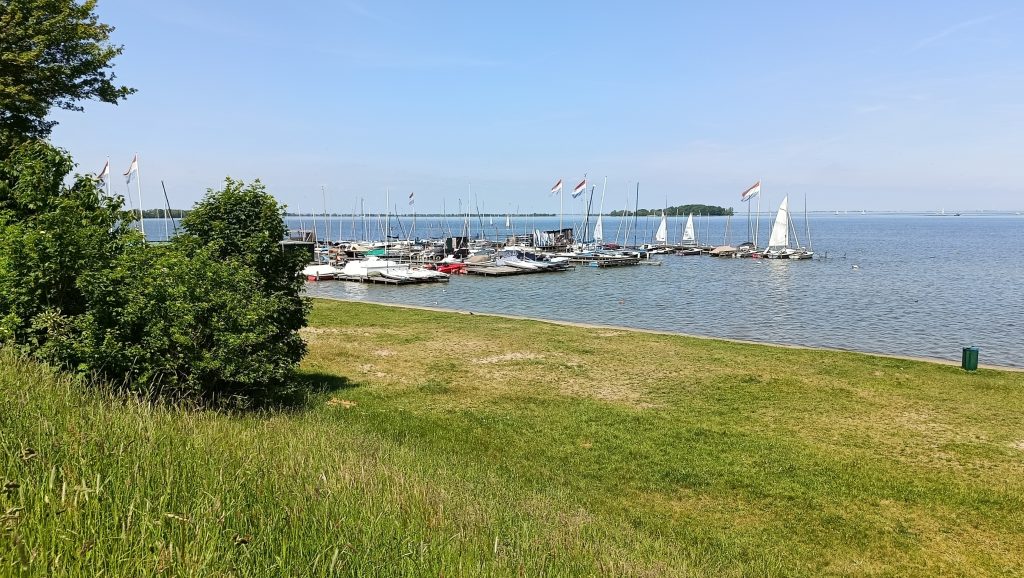 Jachthaven van Muiderberg met zeilboten aan steigers en open water op de achtergrond